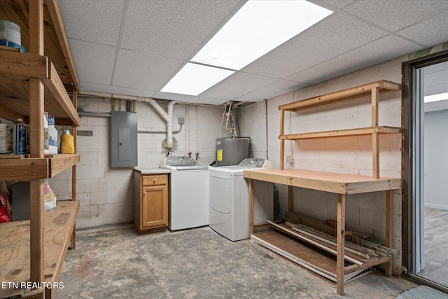 below grade area with water heater, concrete block wall, electric panel, and washing machine and dryer