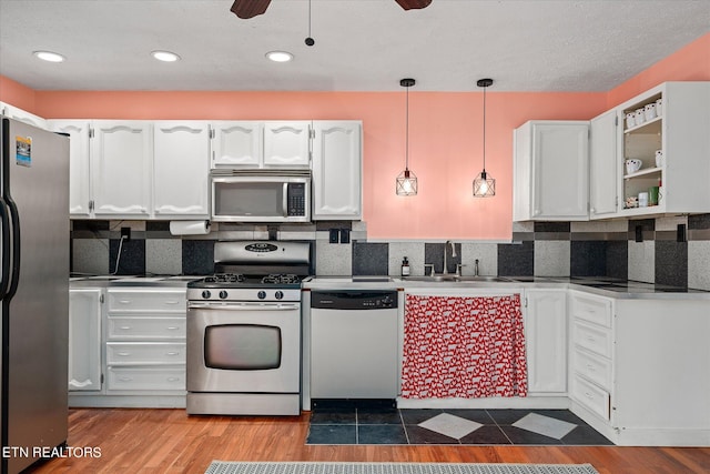 kitchen with wood-type flooring, appliances with stainless steel finishes, sink, and white cabinets