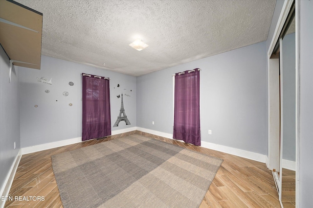 unfurnished bedroom with baseboards, light wood-style floors, and a textured ceiling