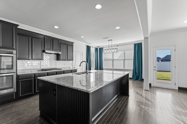 kitchen featuring dark hardwood / wood-style floors, an island with sink, crown molding, sink, and light stone counters