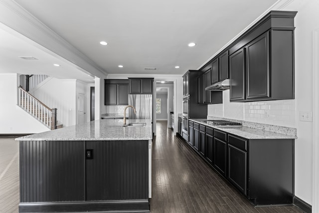 kitchen with decorative backsplash, dark hardwood / wood-style floors, a center island with sink, and ornamental molding