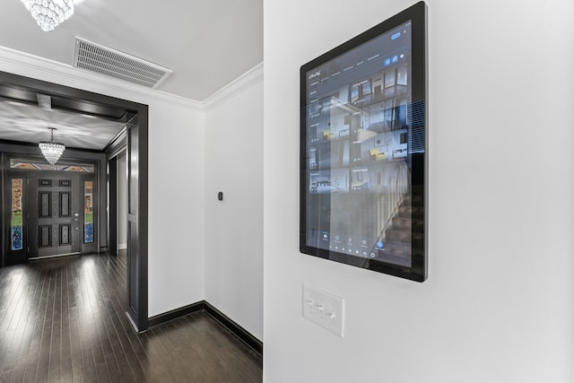 corridor with dark wood-type flooring, crown molding, and an inviting chandelier