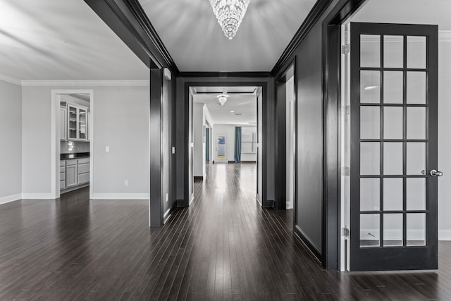 corridor with an inviting chandelier, ornamental molding, and dark hardwood / wood-style flooring