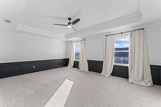 unfurnished bedroom with light carpet, a tray ceiling, and ceiling fan