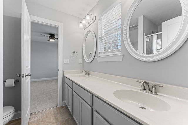 bathroom featuring toilet, ceiling fan, vanity, and a shower with door