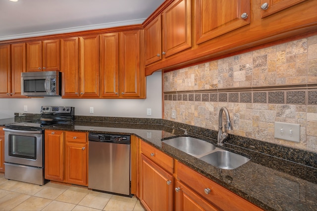 kitchen featuring sink, light tile patterned flooring, stainless steel appliances, and dark stone countertops