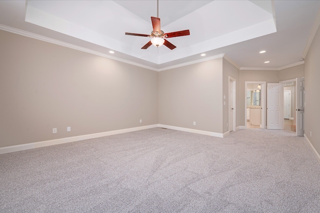 carpeted spare room featuring ornamental molding, a tray ceiling, and ceiling fan