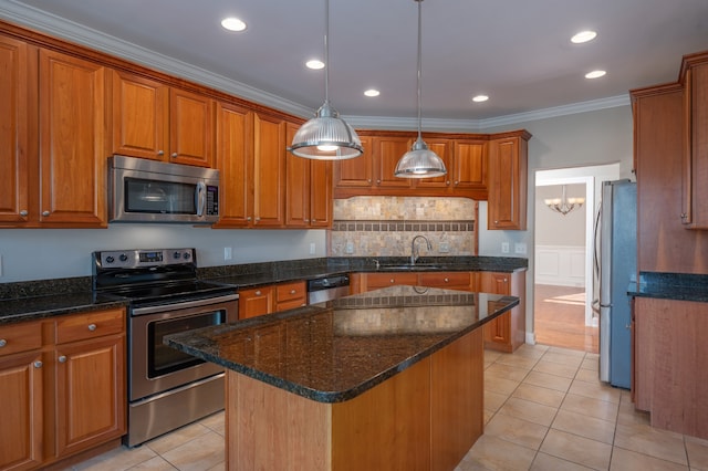 kitchen featuring appliances with stainless steel finishes, sink, a center island, pendant lighting, and ornamental molding