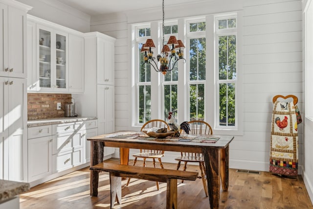 dining room with light hardwood / wood-style flooring, wood walls, and a wealth of natural light