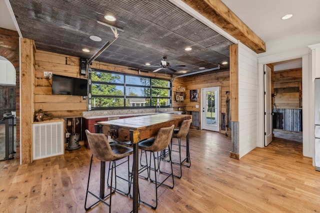 dining room featuring ceiling fan, light hardwood / wood-style floors, and wood walls