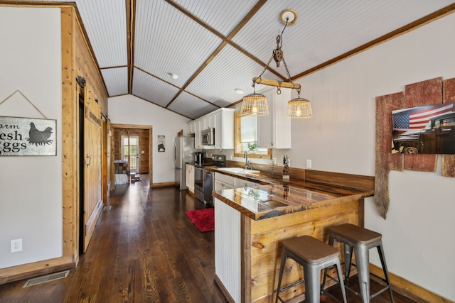 kitchen featuring kitchen peninsula, white cabinets, a kitchen breakfast bar, decorative light fixtures, and stainless steel appliances