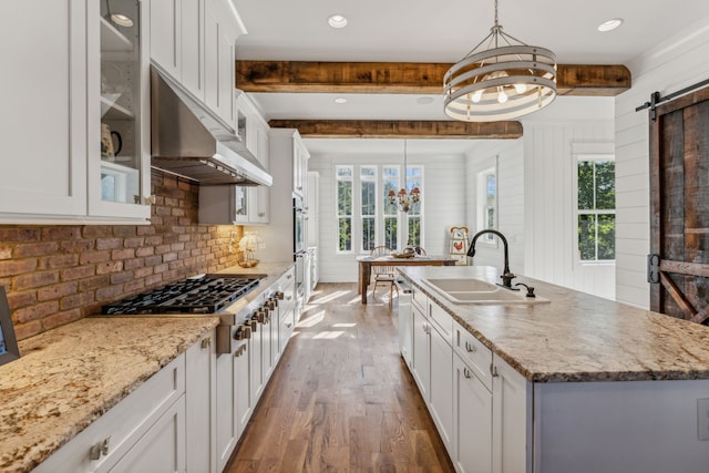 kitchen featuring white cabinets, a barn door, and a center island with sink