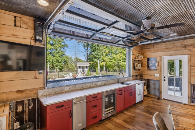 kitchen featuring wine cooler, ceiling fan, dark hardwood / wood-style floors, sink, and wooden walls