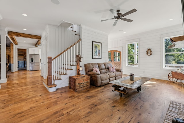 living room featuring light hardwood / wood-style flooring, wooden walls, and ceiling fan