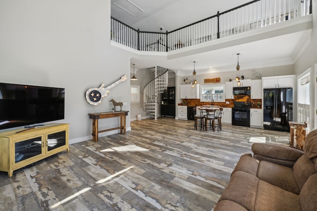 living room with sink, dark wood-type flooring, ornamental molding, and a towering ceiling