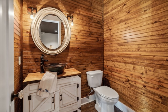 bathroom with vanity, toilet, and wood walls