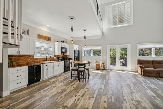 kitchen with black appliances, sink, decorative light fixtures, and white cabinets