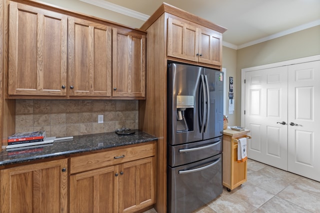 kitchen featuring dark stone countertops, crown molding, decorative backsplash, and stainless steel fridge