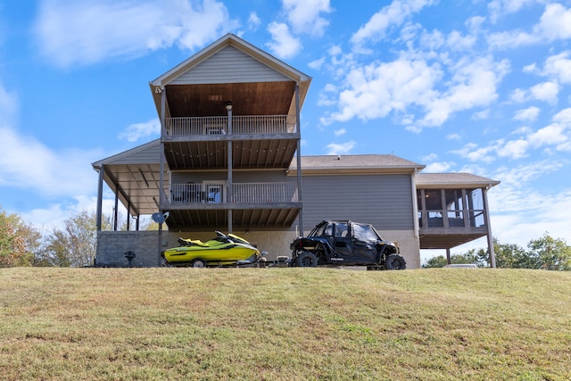 back of property with a yard, a sunroom, and a balcony