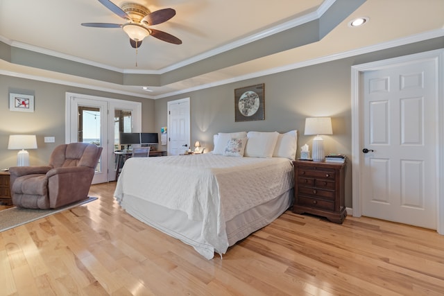 bedroom featuring crown molding, a tray ceiling, light hardwood / wood-style floors, and ceiling fan