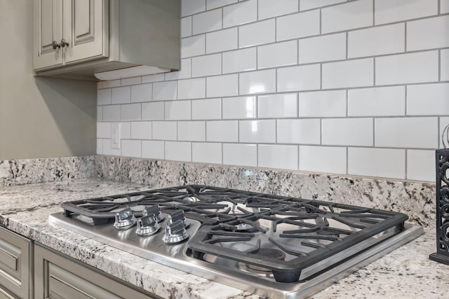 room details with stainless steel gas cooktop, light stone counters, and backsplash