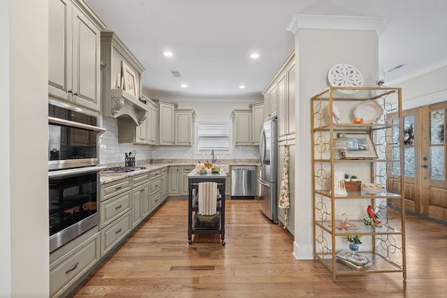 kitchen with light hardwood / wood-style flooring, stainless steel appliances, a center island, gray cabinets, and tasteful backsplash