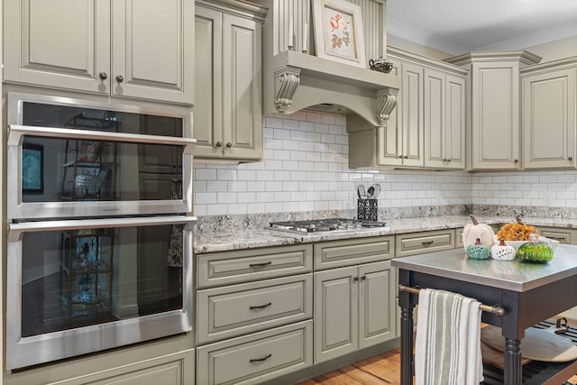 kitchen featuring backsplash, light stone countertops, stainless steel appliances, and light wood-type flooring