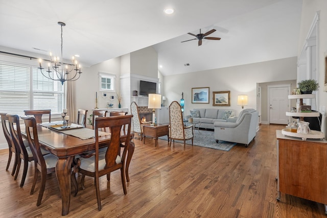 dining space with ceiling fan with notable chandelier, high vaulted ceiling, and dark hardwood / wood-style floors