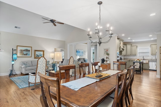 dining area with ornate columns, light hardwood / wood-style flooring, ceiling fan with notable chandelier, and vaulted ceiling