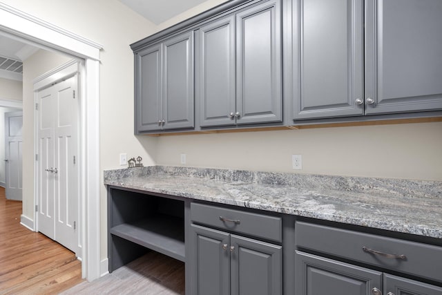 kitchen with gray cabinets, light stone countertops, and light hardwood / wood-style floors