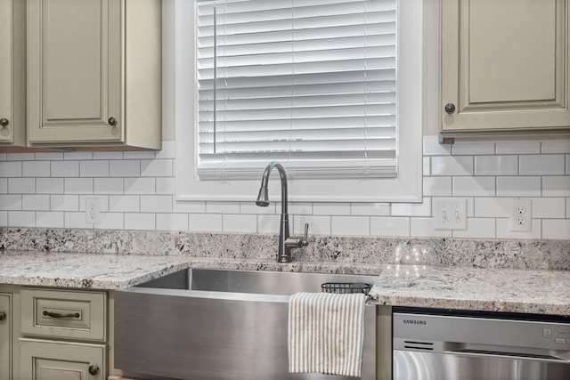 kitchen with cream cabinets, backsplash, sink, stainless steel dishwasher, and light stone counters