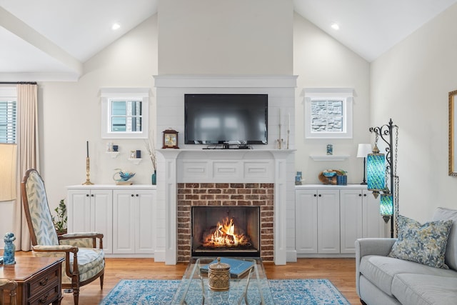 living room featuring light hardwood / wood-style flooring, a brick fireplace, and high vaulted ceiling