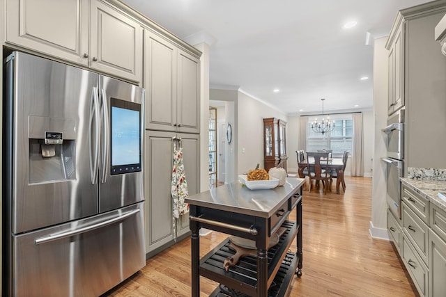 kitchen with light hardwood / wood-style flooring, ornamental molding, light stone countertops, and stainless steel appliances