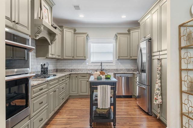 kitchen featuring tasteful backsplash, appliances with stainless steel finishes, light wood-type flooring, custom range hood, and light stone counters