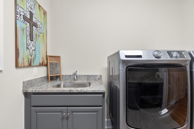 clothes washing area with sink, separate washer and dryer, and cabinets