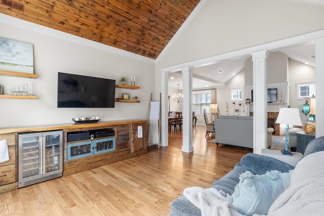 living room featuring wine cooler, high vaulted ceiling, a chandelier, and light hardwood / wood-style floors