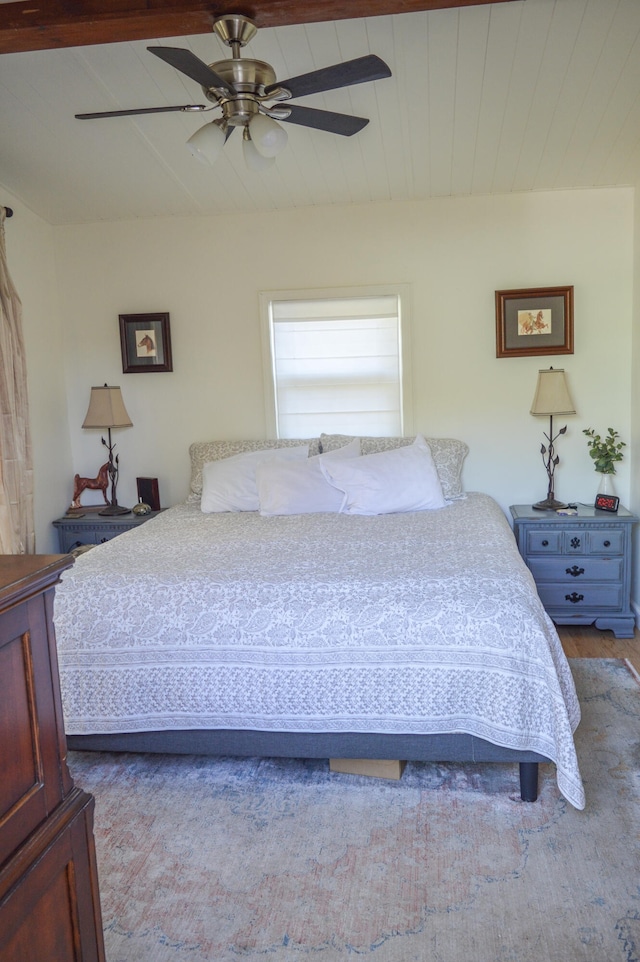 bedroom featuring ceiling fan, beamed ceiling, and hardwood / wood-style floors