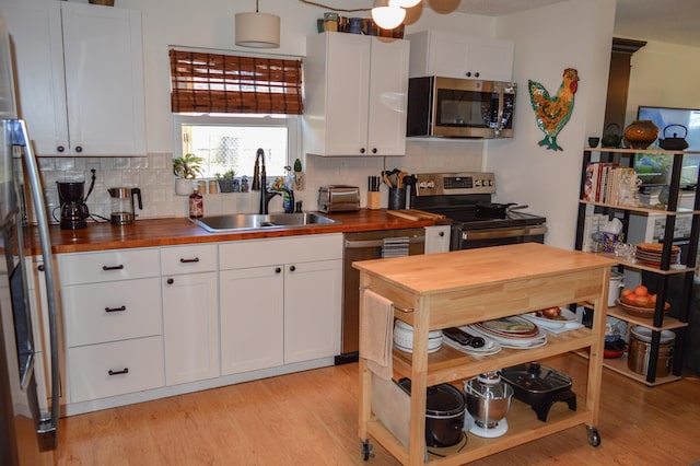 kitchen featuring sink, white cabinets, stainless steel appliances, and wood counters