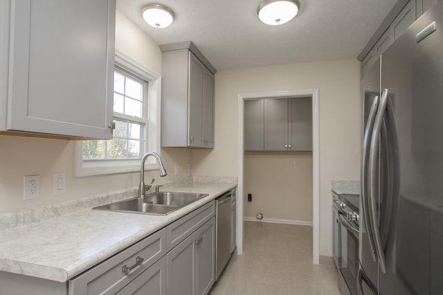 kitchen featuring appliances with stainless steel finishes, a textured ceiling, sink, and gray cabinetry