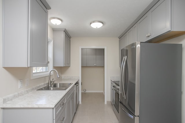 kitchen with appliances with stainless steel finishes, a textured ceiling, sink, and gray cabinets