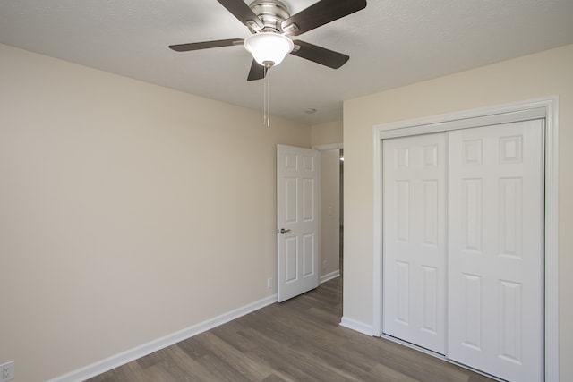 unfurnished bedroom featuring a closet, a textured ceiling, dark wood-type flooring, and ceiling fan