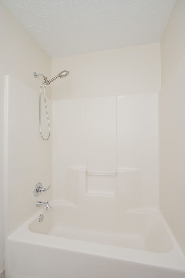 bathroom featuring a textured ceiling and tub / shower combination