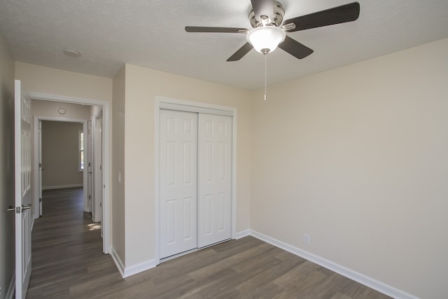 unfurnished bedroom featuring a closet, ceiling fan, a textured ceiling, and dark hardwood / wood-style floors