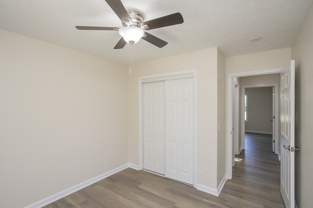 unfurnished bedroom with a closet, ceiling fan, hardwood / wood-style flooring, and a textured ceiling