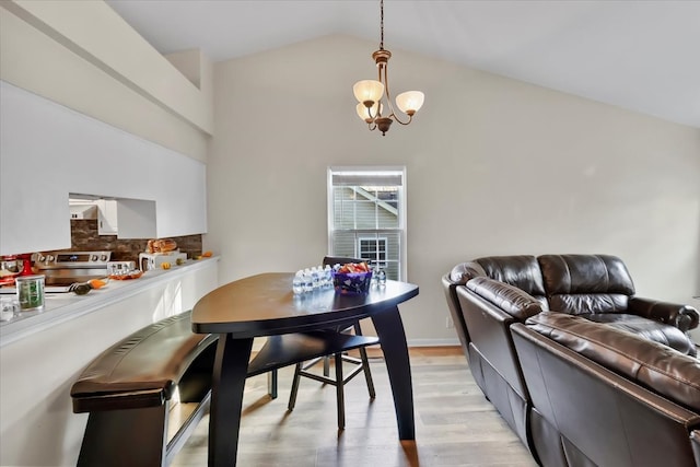 dining space with vaulted ceiling, an inviting chandelier, and light hardwood / wood-style flooring