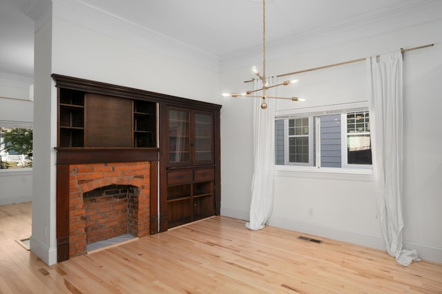 unfurnished living room featuring plenty of natural light, crown molding, light wood-type flooring, and a fireplace