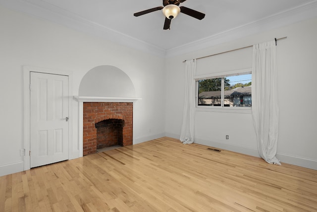 unfurnished living room featuring ornamental molding, a brick fireplace, light wood-type flooring, and ceiling fan