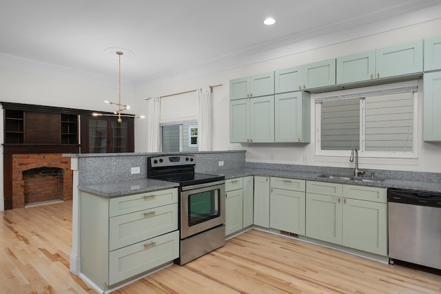 kitchen with appliances with stainless steel finishes, light wood-type flooring, dark stone counters, sink, and decorative light fixtures