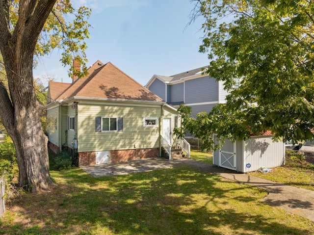 back of property with a shed, a patio area, and a lawn