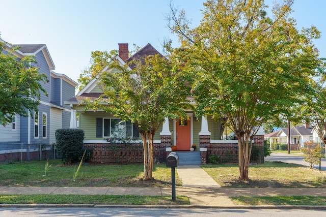 obstructed view of property featuring covered porch and a front yard